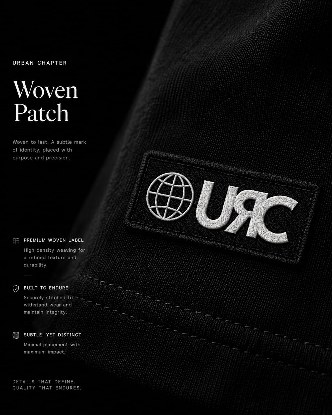 Extreme macro photography of the Urban Chapter woven applique patch stitched onto the lower hem of the heavyweight black YU artifact.