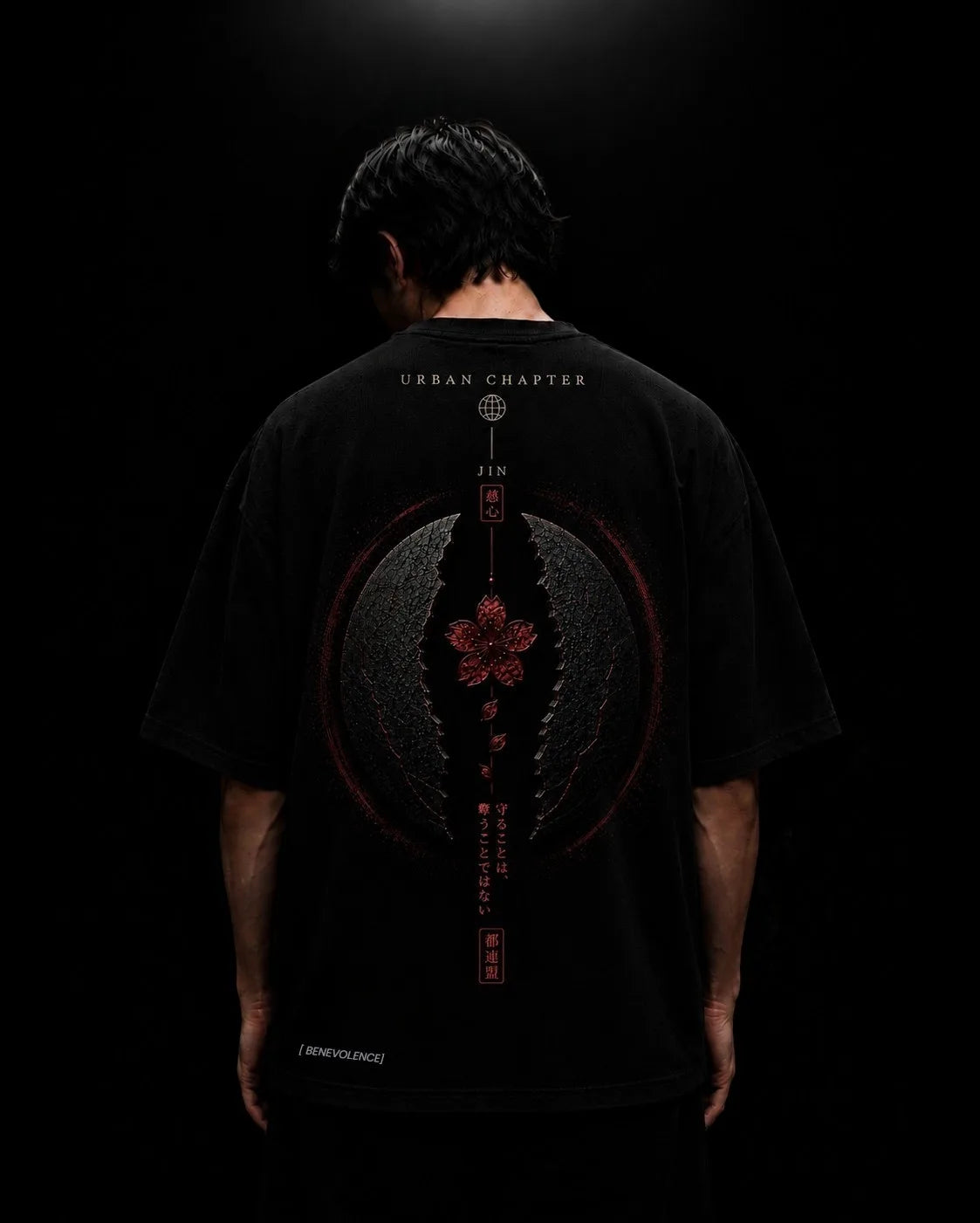 Reverse view of a figure wearing the oversized JIN artifact, revealing the heavy drape and the imposing central composition that transforms the garment into a wearable relic from the Urban Chapter universe.