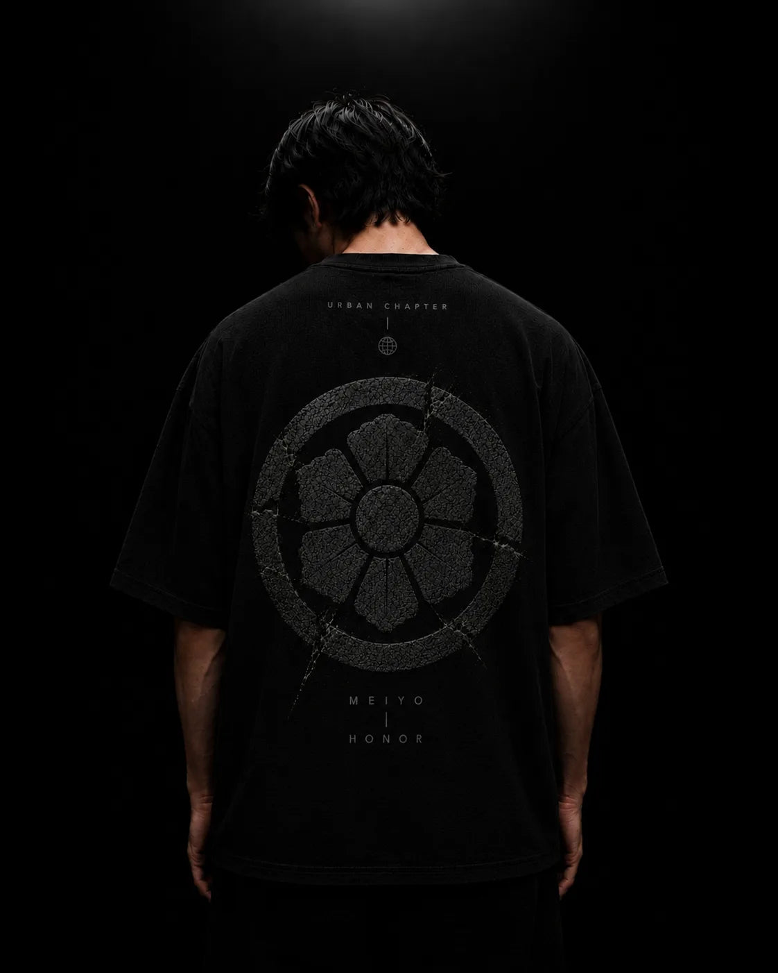 Extreme macro photography of dense 260 GSM black French terry showcasing the raised satin-embroidered MEIYO crest, where every stitch creates depth, structure, and ceremonial precision.