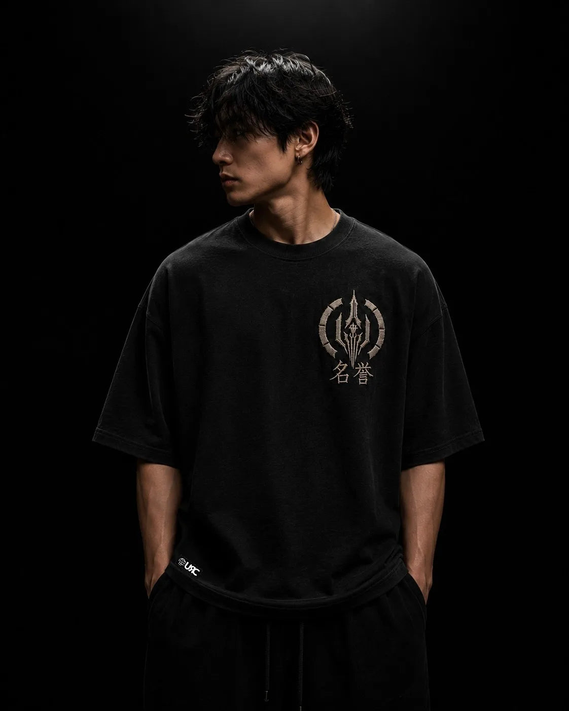 Solitary figure wearing the oversized black MEIYO artifact, highlighting the engineered drop-shoulder silhouette and elevated satin embroidery construction.